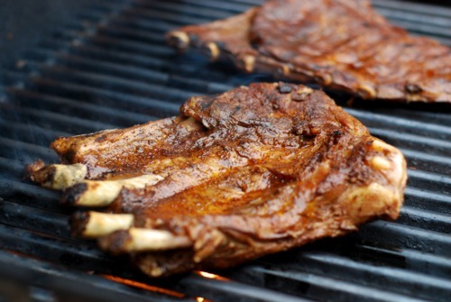 Two racks of pork ribs searing on a hot grill.