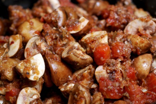 A slow cooker is filled with ingredients for a chicken cacciatore recipe.
