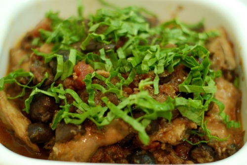 Slow cooker chicken cacciatore is in a microwave safe bowl topped with chiffon fresh basil.
