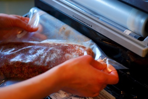 A close up of a pork loin in a plastic bag getting ready to be vacuum sealed.
