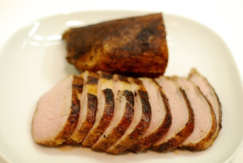 A plate of pork loin cooked by sous vide is cut up into thin slices and presented on a white plate.