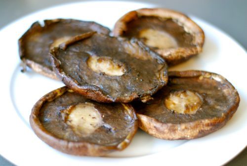 The tops of portobello mushrooms baked and cooling on a plate.