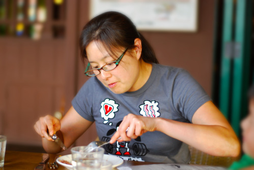 An Asian woman eating at a table.