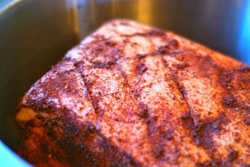 A pork roast in a silver bowl after marinating in the fridge.