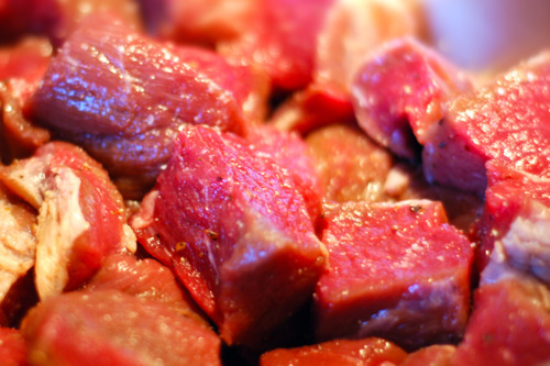 Cubes of beef brisket are seasoned with salt and pepper.