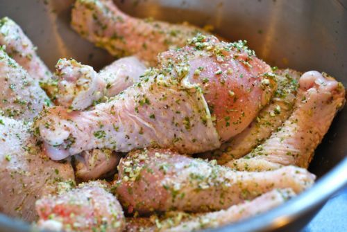 Raw chicken drumsticks in a bowl marinating for Braised Chicken With Artichokes and Pearl Onions.