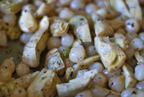 Frozen onions, artichokes, and garlic are added to a skillet.