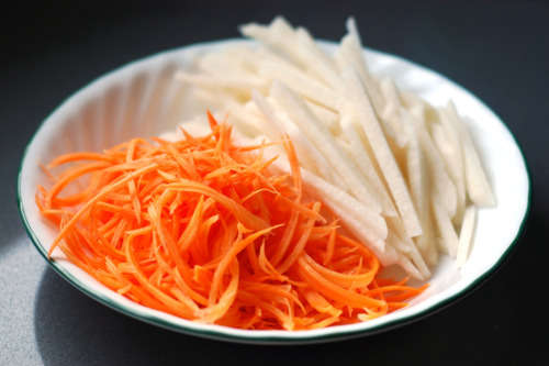 Thinly sliced jicama and carrots prepped in a bowl for surf and turf lettuce tacos.