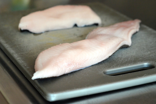 Two black cod fillets on a cutting board.