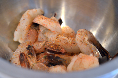 Defrosted shrimp in a metal bowl with seasoning.