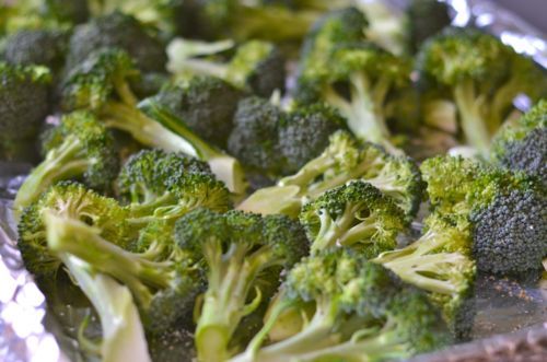 Broccoli florets on a half sheet pan ready to be baked in the oven.