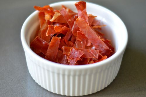 Baked prosciutto cut into thin strips and piled in a small bowl.