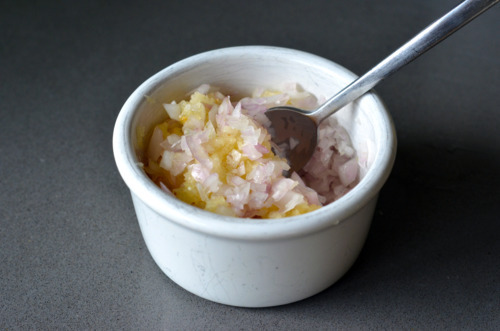 Minced garlic and shallots in a small ramekin with a spoon sticking out of it.