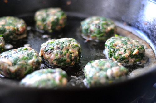 The beef, spinach and mushroom mini burgers frying in a cast iron skillet.
