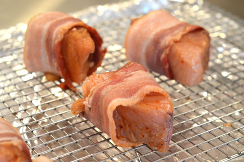 Bacon-wrapped tuna medallions on a wire rack ready to be baked in the oven.