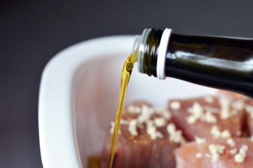 Pouring olive oil into the oven-safe dish with the tuna steaks.