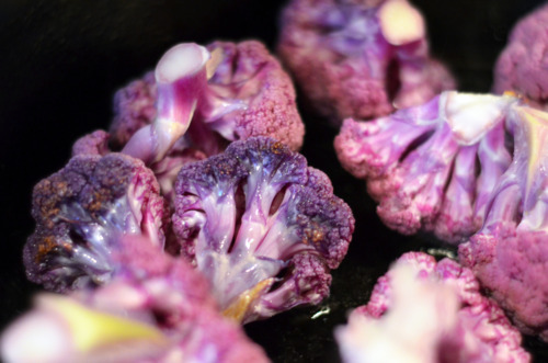 Frying purple cauliflower florets in a cast iron skillet.