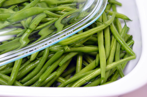 Green beans sitting in a white container ready for the microwave.