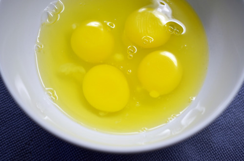 Four cracked eggs in a bowl.