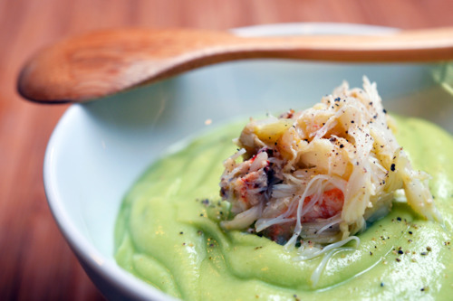 Chilled cream of avocado soup in a bowl topped with seasoned Dungeness crab.