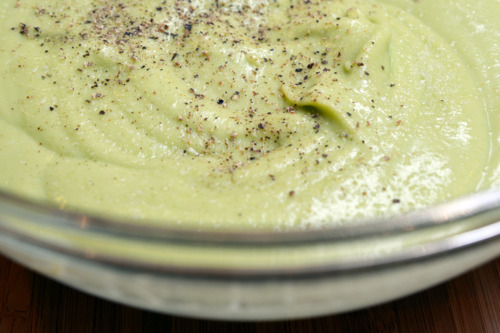 A bowl of avocado cream soup with salt and black pepper on top.