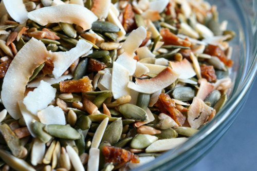 A bowl of paleo trail mix filled with sunflower seeds, pumpkin seeds, almond slivers, dried pineapple, and dried coconut.