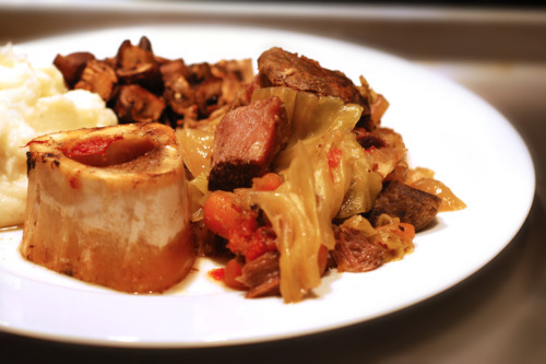 A plate with slow cooker grass fed beef shanks and cabbage stew.