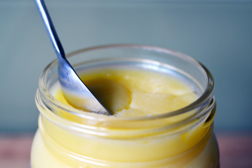 A jar of ghee with a spoon scooping out ghee.