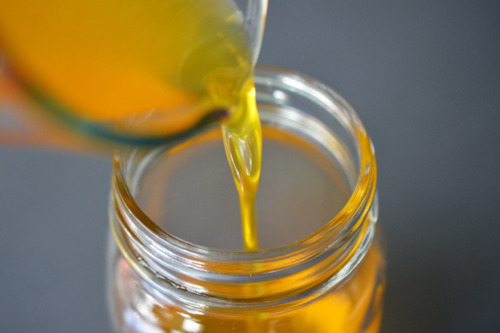 Pouring the melted butter into a glass jar to make ghee.
