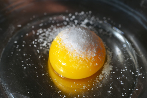 Picture of a raw egg yolk in a bowl with salt on top.