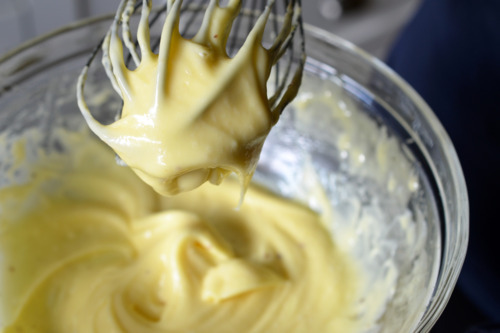 Closeup of thick and creamy mayonnaise on a whisk and in the bowl.