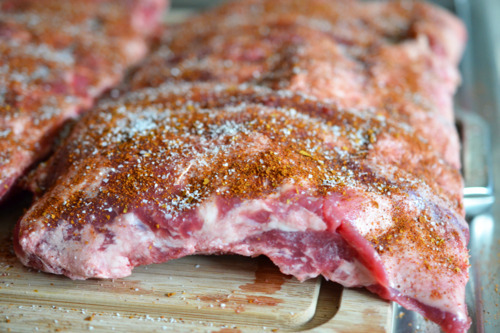 Raw ribs on a cutting board seasoned and salted.