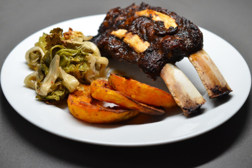 A plate of pressure cooked ribs with sides of vegetables.