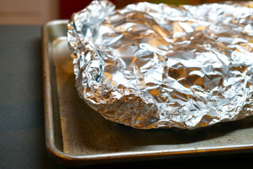 Foil-wrapped ribs on a baking sheet ready to be cooked.