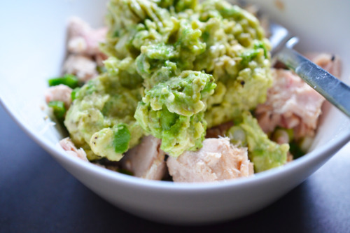 Guacamole added to a bowl of canned tuna for tuna and avocado wraps.