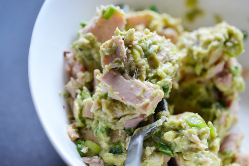Mixing guacamole and canned tuna in a bowl with a fork.