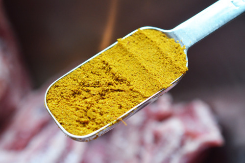 One tablespoon of yellow curry powder being added to an instant pot for Instant Pot Indian Curry Lamb Spare Ribs.