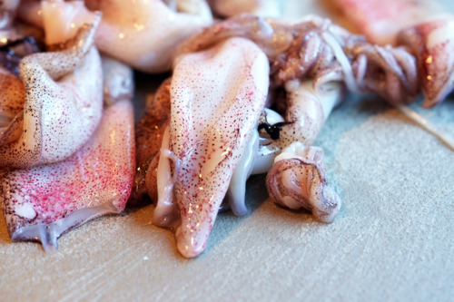 A pile of raw squid on a cutting board.