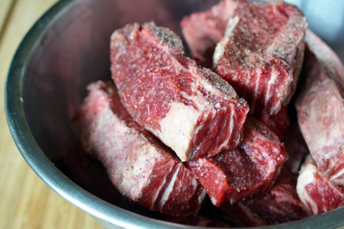 Salt and pepper seasoned beef short ribs in a metal bowl.