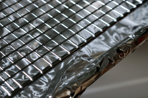 Lining a baking sheet with aluminum foil and putting a wire rack on top.