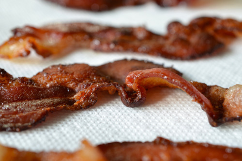 Crispy and cooked bacon drying on a paper towel.