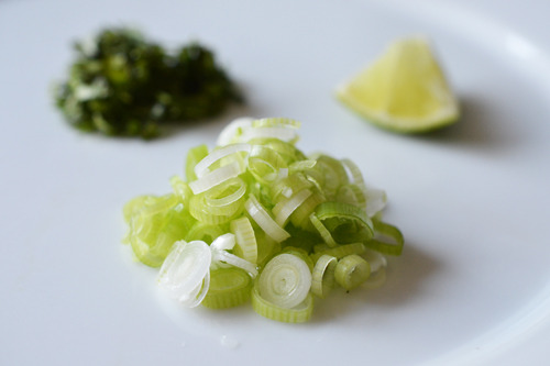 A mise en place of cilantro, scallions, and limes for Thai rolled omelet.