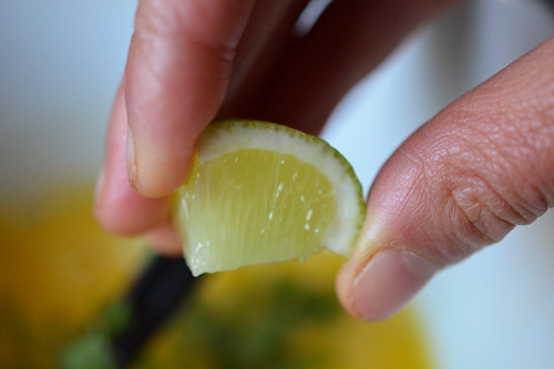 Squeezing fresh lime into the bowl of mixed eggs.