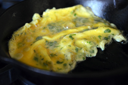 A closeup of the eggs cooking in a cast iron skillet.