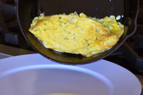 Transferring the cooked omelet to a plate.