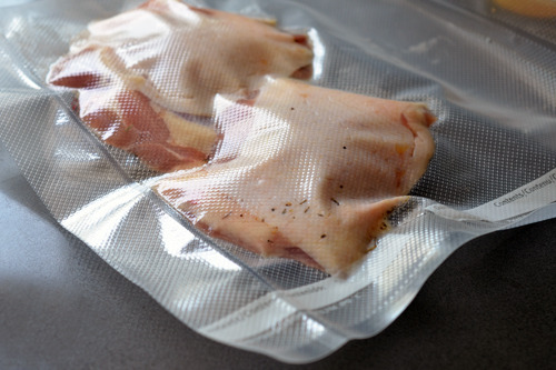 Vacuum sealed chicken thighs with a pat of butter preparing for sous vide.