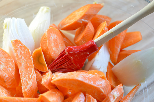 Closeup of a bowl with butter-coated carrots, yams, and onions.