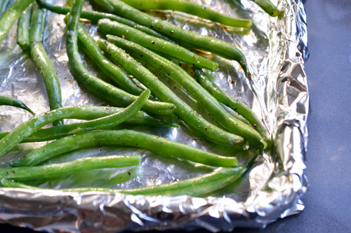 The seasoned green beans are placed in a single layer on a foil-lined rimmed baking sheet.