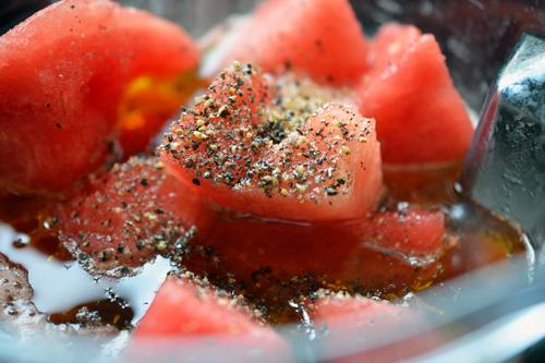 Adding the watermelon, vinegar, olive oil, salt, and pepper into the blender with the blended vegetables.