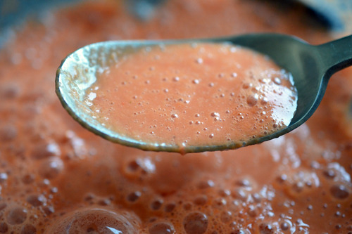 A closeup of a spoonful of watermelon and tomato gazpacho.
